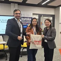 A pair of people grasp a bag marked with a sign, suggesting collaboration or an important announcement.