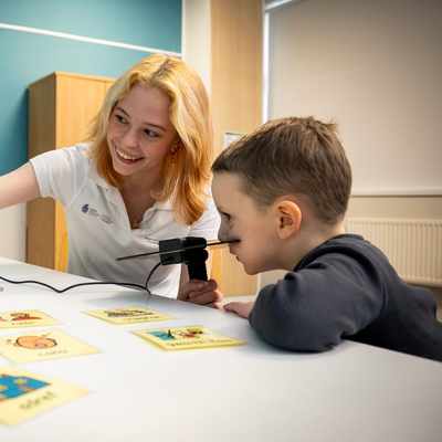 A young woman points to a laptop screen in an educational moment for the young child sat next to them