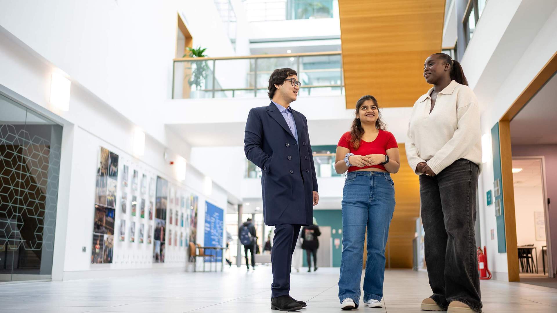 Three people standing in a brightly lit atrium space.