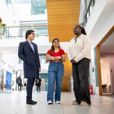 Three people standing in a brightly lit atrium space.