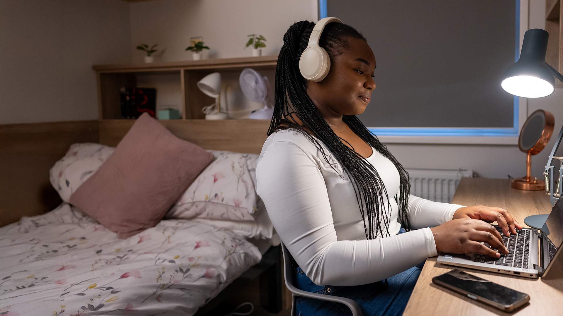 A woman wearing headphones sits at a desk, focused on her laptop, creating a productive work environment.