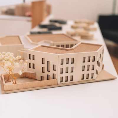 A replica office building made from wood sits on a white desk