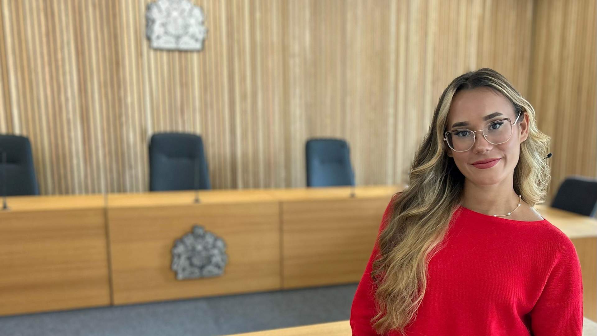 A group of six students is standing outside Cardiff Metropolitan University. One student is taking a selfie while the others smile and pose. The university building is visible in the background under a partly cloudy sky.