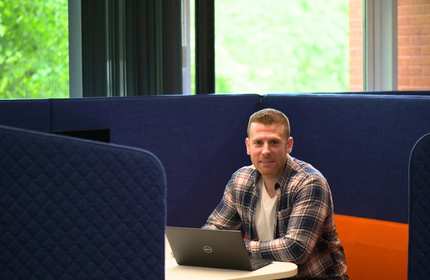 Chris Ohanyan sits at a desk within a study booth while using a laptop