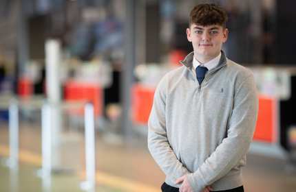 A person stands in front of a row of airport check-in desks.