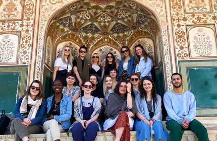 A group of people pose for a photo in front of an ornately decorated wall