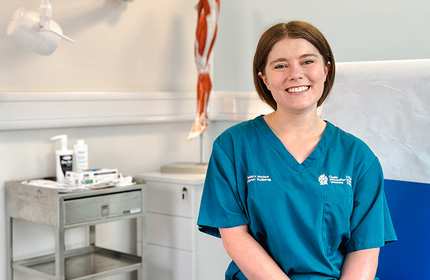 Jenny Craggs, wearing blue nurses uniform, sits in a practice room