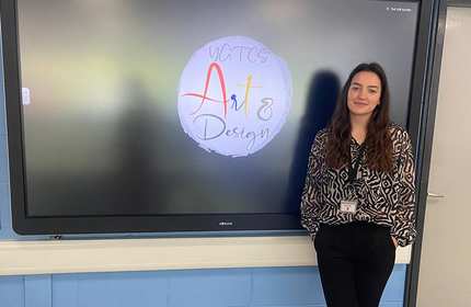 Maia White, stands in front of an electronic display board
