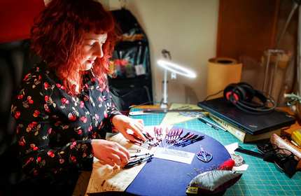 Simone lays out and adjusts the position of her sewing tools on a desk