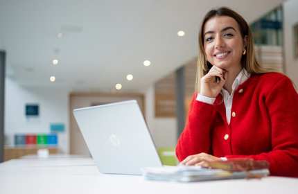 Xhevilta Rizani sits at a long desk in front of a laptop and writing pad