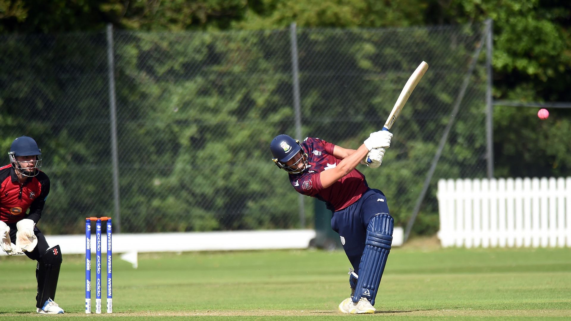 A cricket player swings their bat at the ball during a match