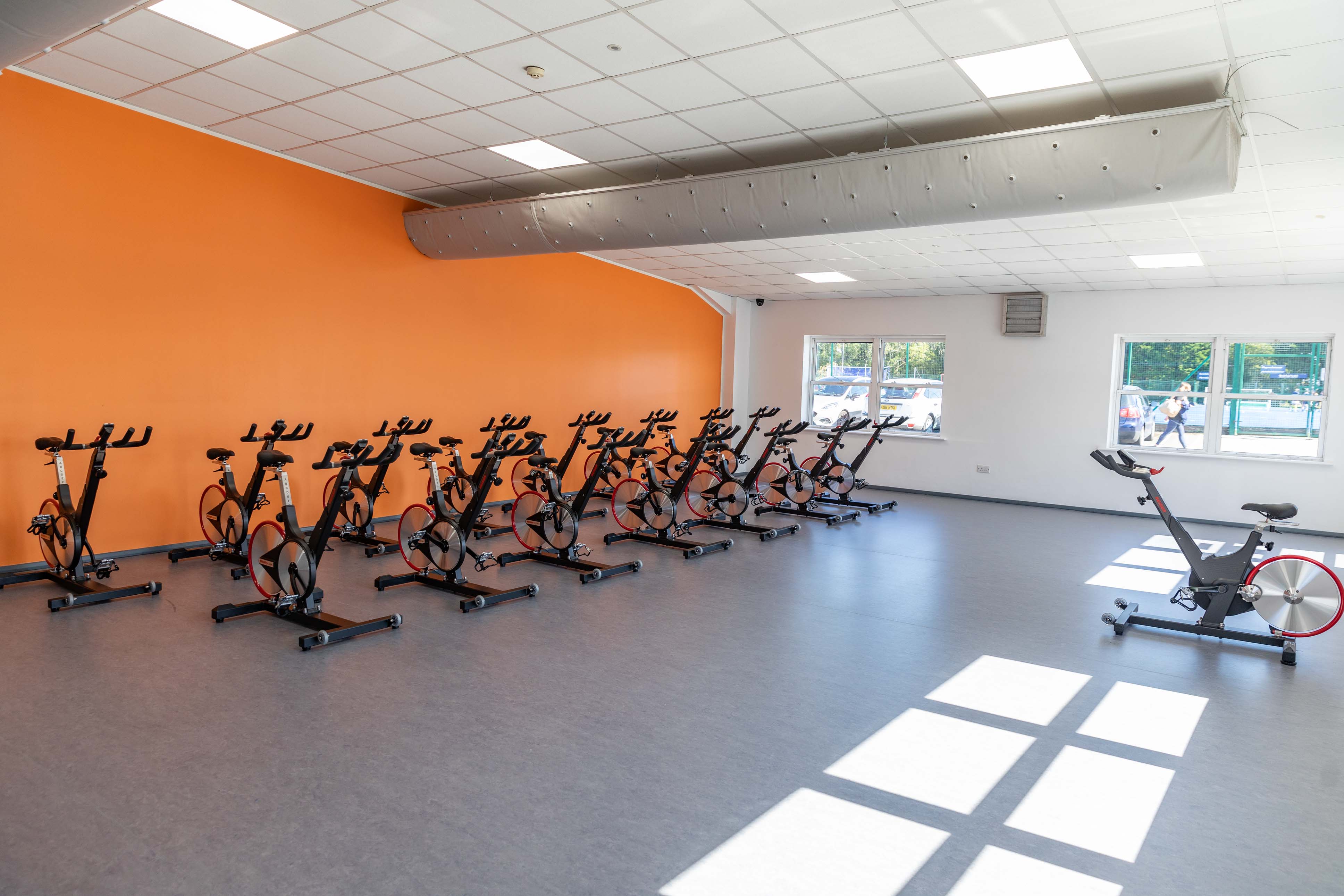 Two rows of spin bikes face one spin bike for an exercise class