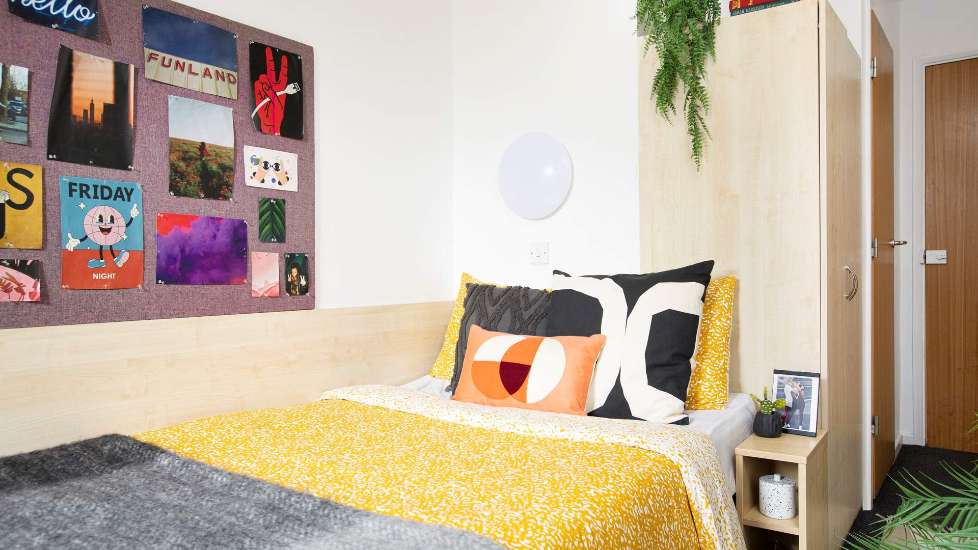 A decorated bedroom complete with posters hanging on a display board and made up bed