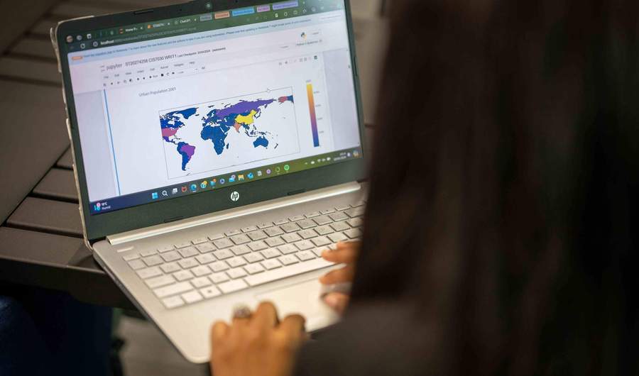 A close-up of a laptop computer. On the laptop screen is a map of the world.