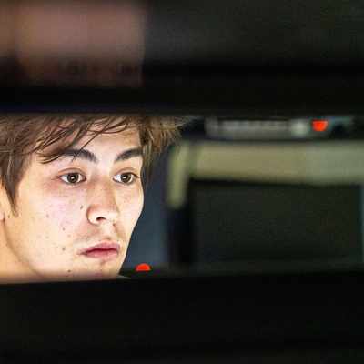 A close-up of a person looking at a computer monitor. Their face is lit from the light of the screen.