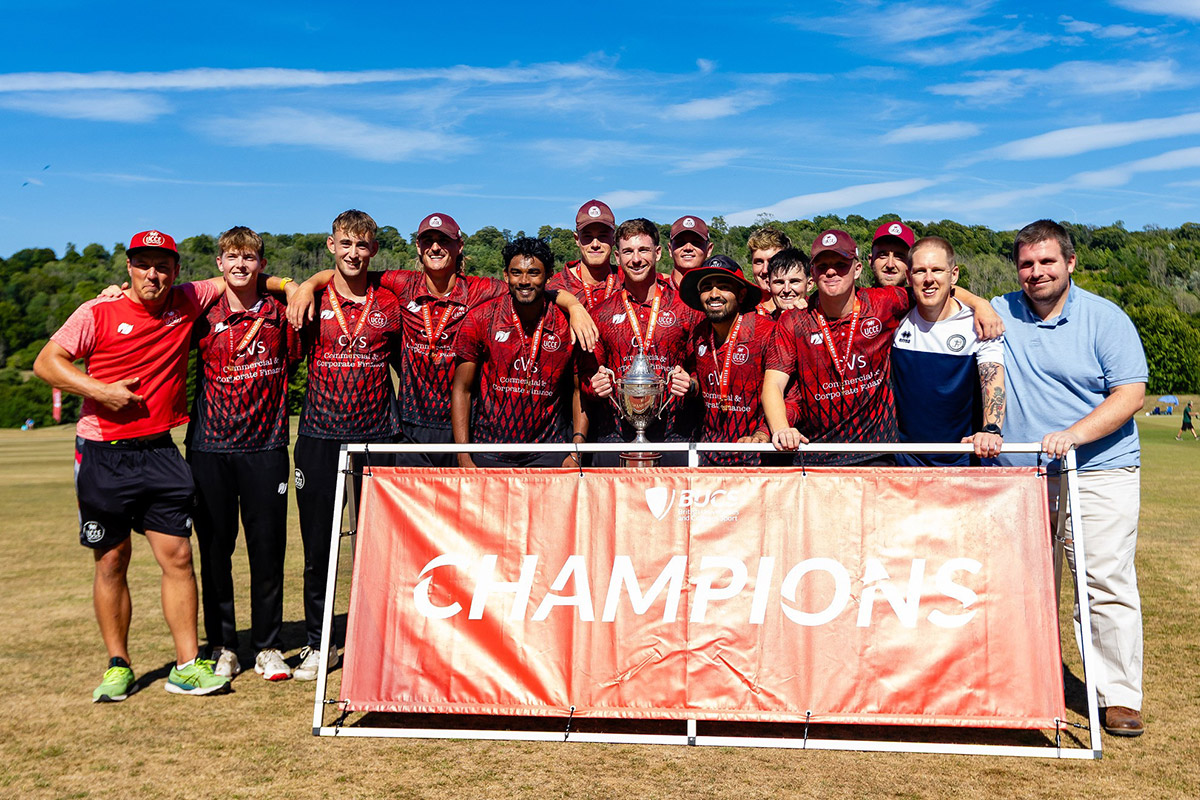 Several men are gathered in front of a banner saying Champions, displaying a sense of camaraderie and engagement.