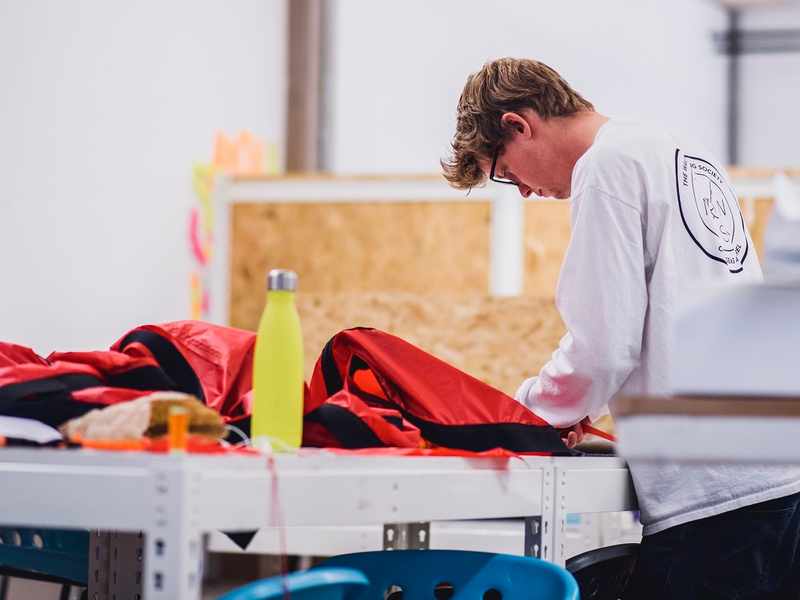 A student works on a large piece of red fabric in an art and design workshop