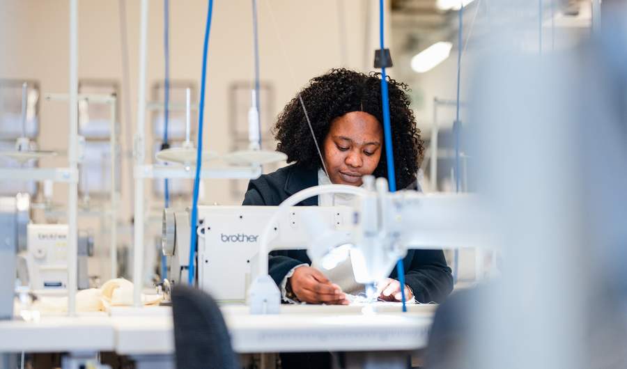 A young woman works at a sewing machine
