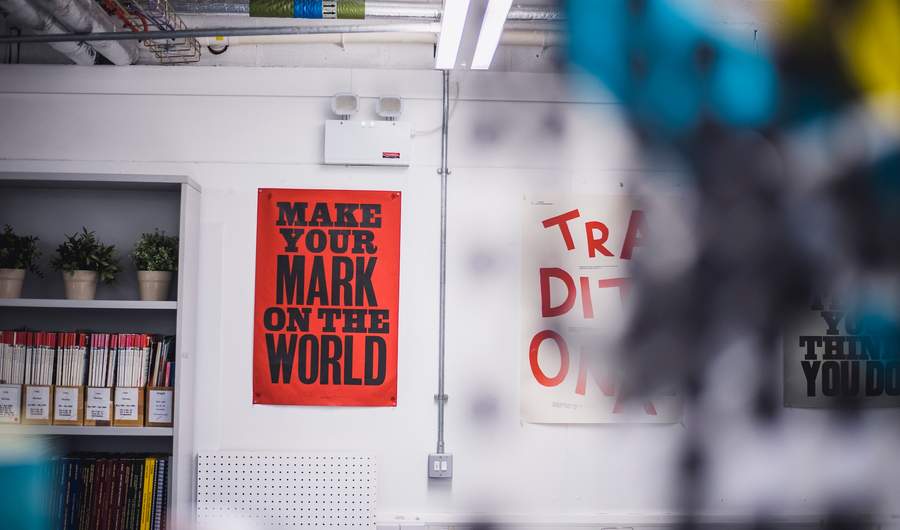 Two artistic posters displayed on a white workshop wall