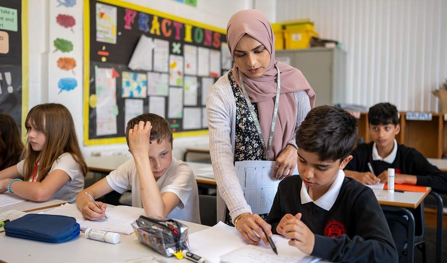 A teacher points to a pupils worksheet as they work in the classroom