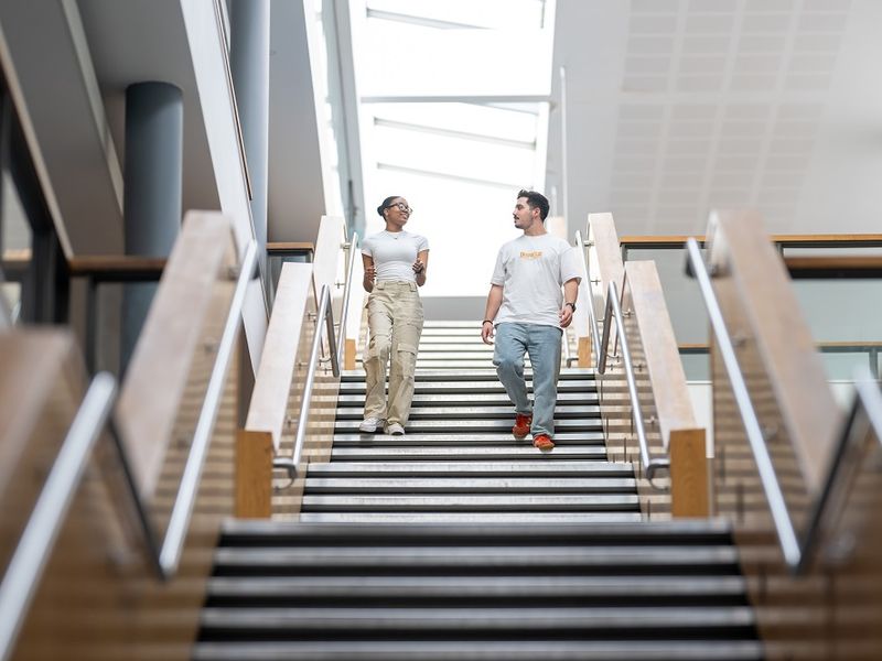 Two students walk down the stairs of the Cardiff School of Management