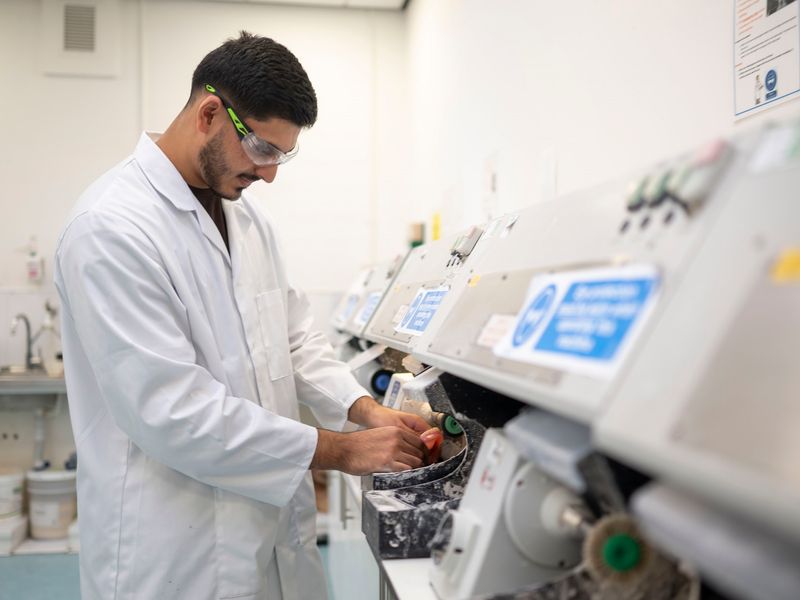 A young adult in white laboratory uniform places his hands in a medical machine