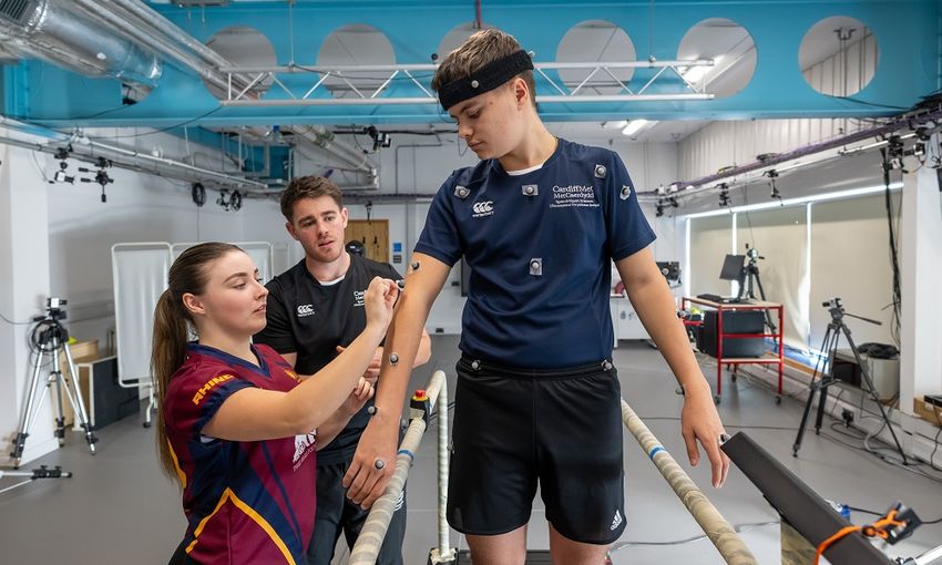 A young adult is having nodes attached to be monitored while moving on a treadmill