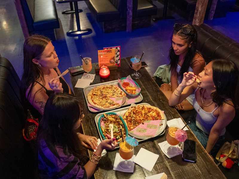 A group of students sit around a table sharing some street food.
