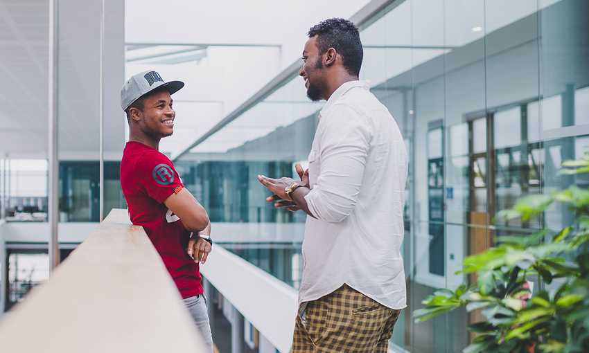 Two men having a discussion in an office building, highlighting a collaborative work atmosphere.