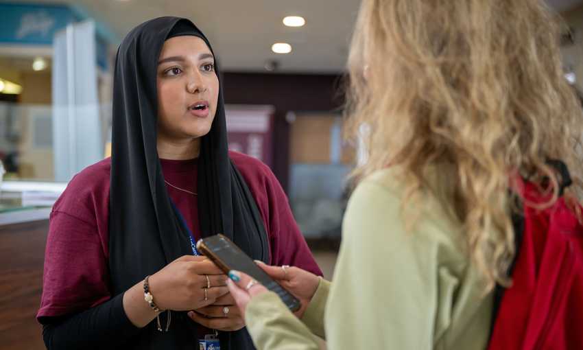 A woman in a hijab engages in conversation with another woman, showcasing a moment of connection and dialogue.