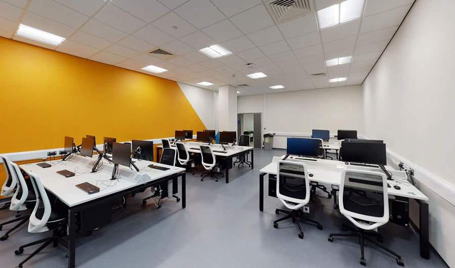 Clusters of work desks with office chair and computer screens in office room.