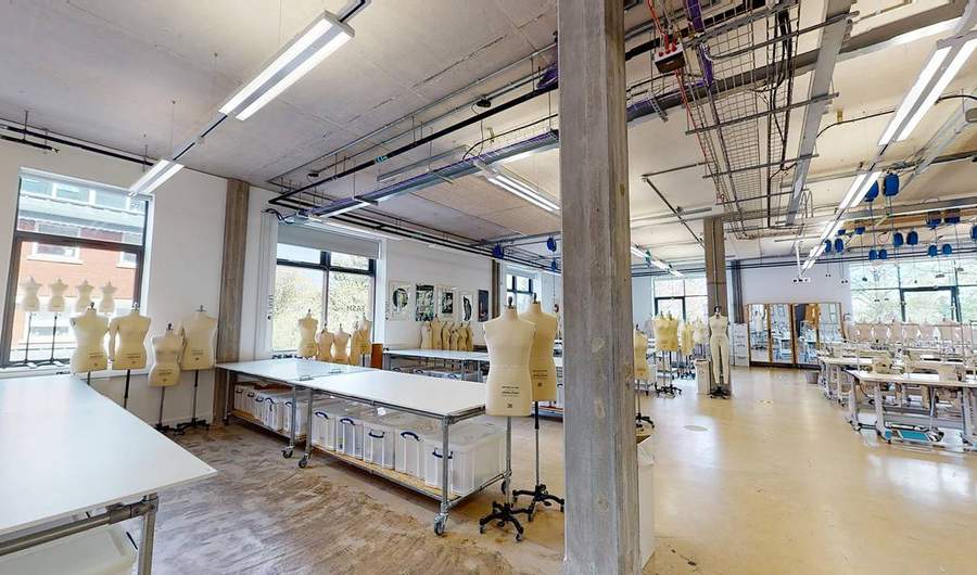 Rows of tables in a large room, with tailor's dummies and sewing machines