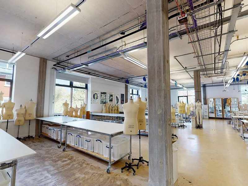 Rows of tables in a large room, with tailor's dummies and sewing machines