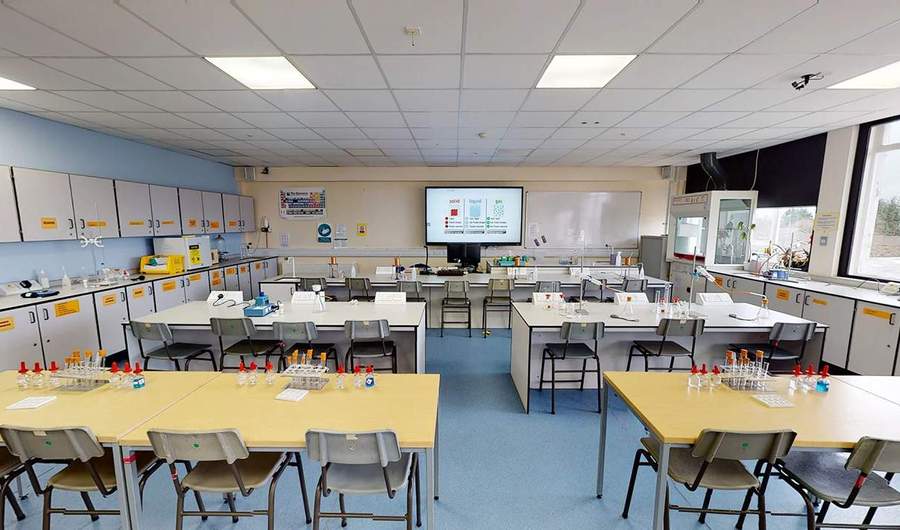 A large room with three rows of desks. On the desks are test tubes and beakers.