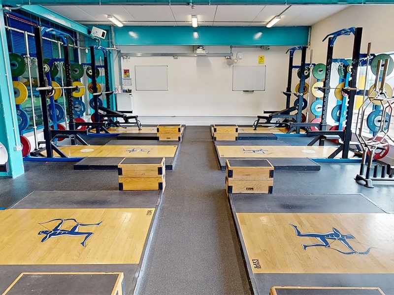 A gym with multiple lifting platforms, squat racks, and weights.