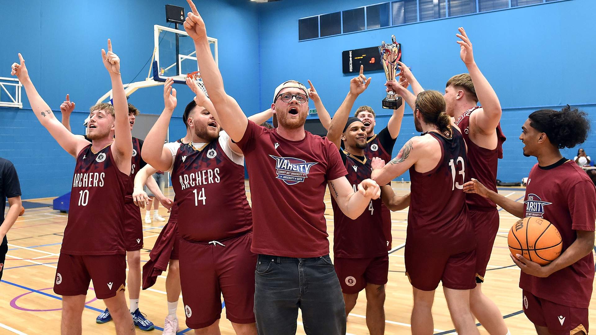 The varsity basketball team celebrates on the court after winning a game