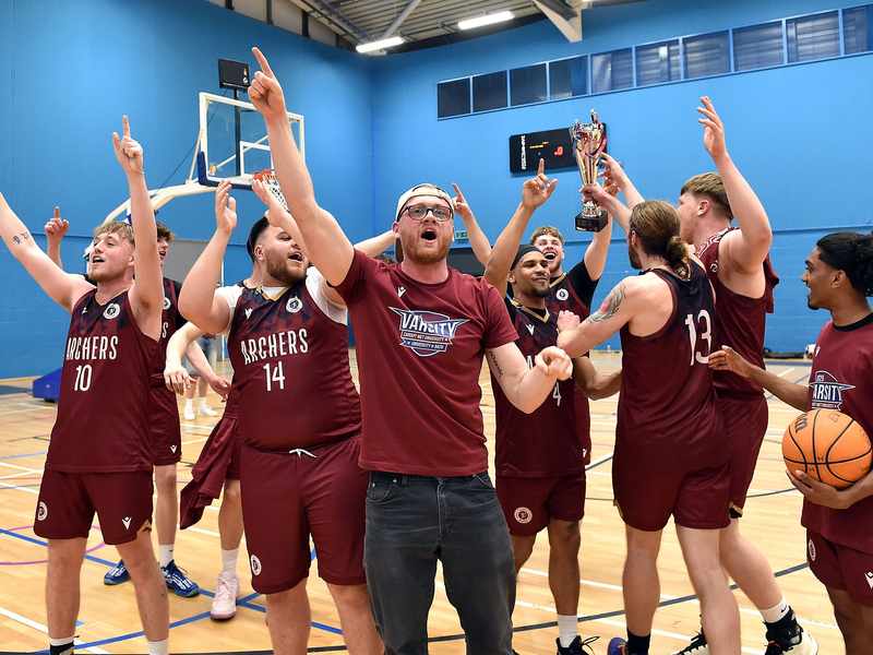 The varsity basketball team celebrates on the court after winning a game