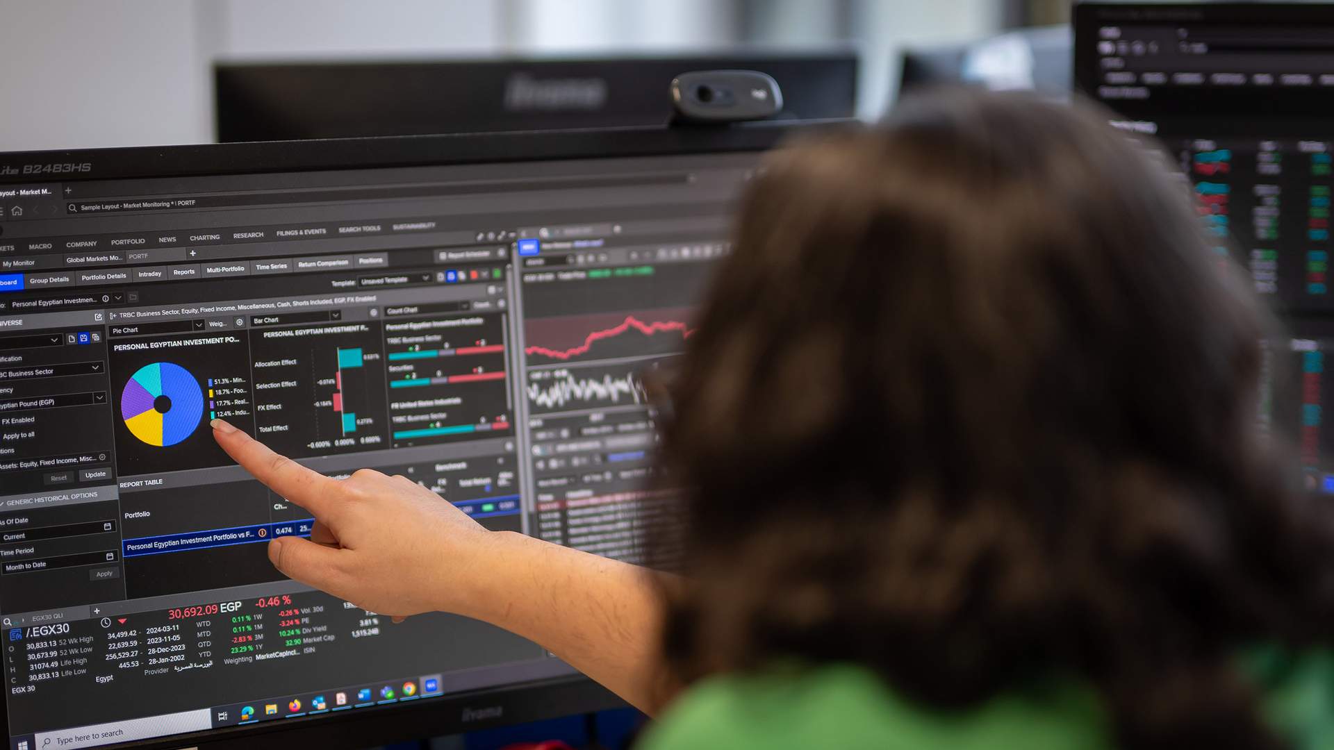 A person in a yellow jacket smiles in front of a modern building with the Cardiff Metropolitan University sign. The sky is overcast, and the building has illuminated lights.