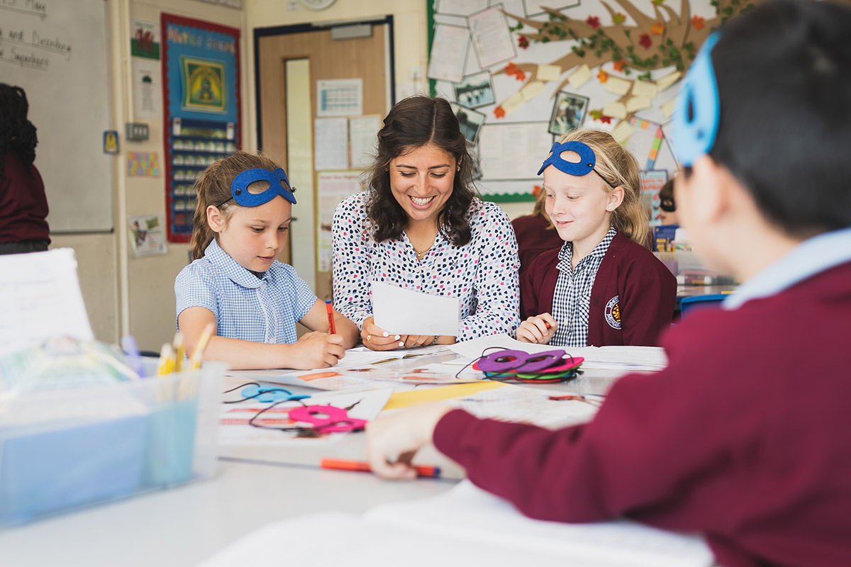 A teacher assists children with their class work, providing guidance and support in a classroom setting.