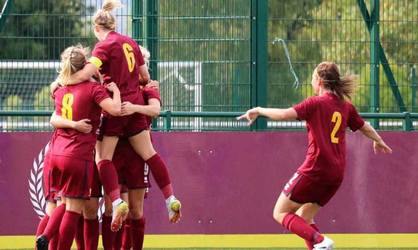 A group of Cardiff Metropolitan University FC Women's team celebrate a goal in a huddle