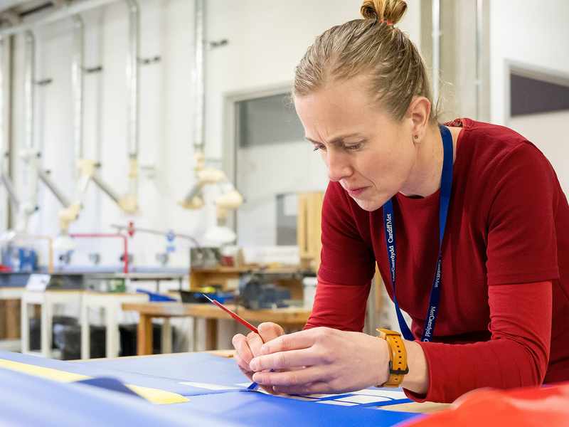 A woman engages in project work at her desk in a classroom, demonstrating concentration and creativity in her task.