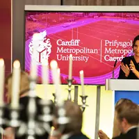A woman delivering a speech at a formal dinner event, engaging the audience with her presentation.