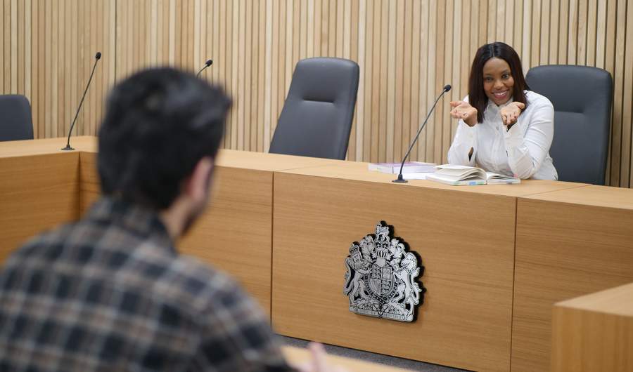 A person sits facing a courtroom bench.