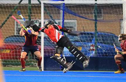 Hockey keeper stretches their stick to make a save during a game of hockey