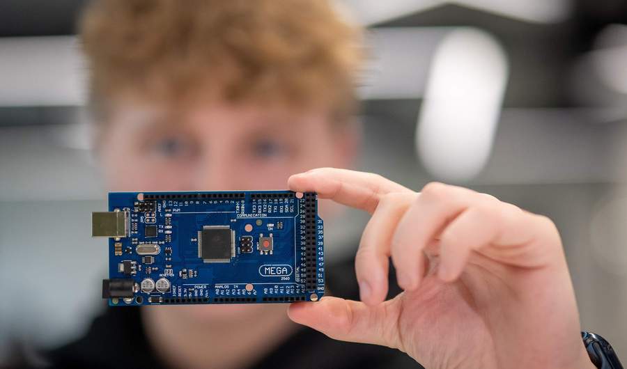 A person holds a micro-controller circuit board.