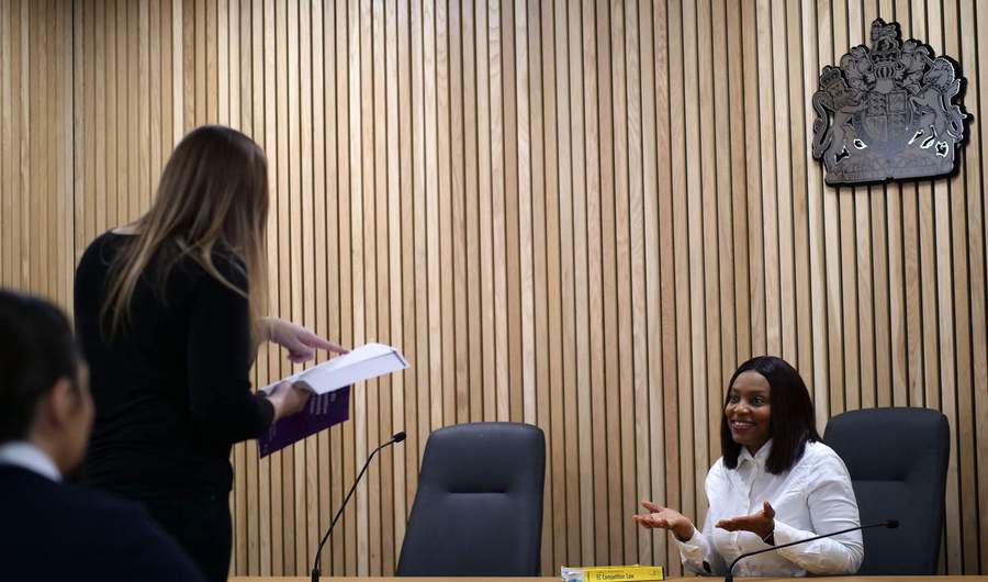 A person stands facing a courtroom bench.