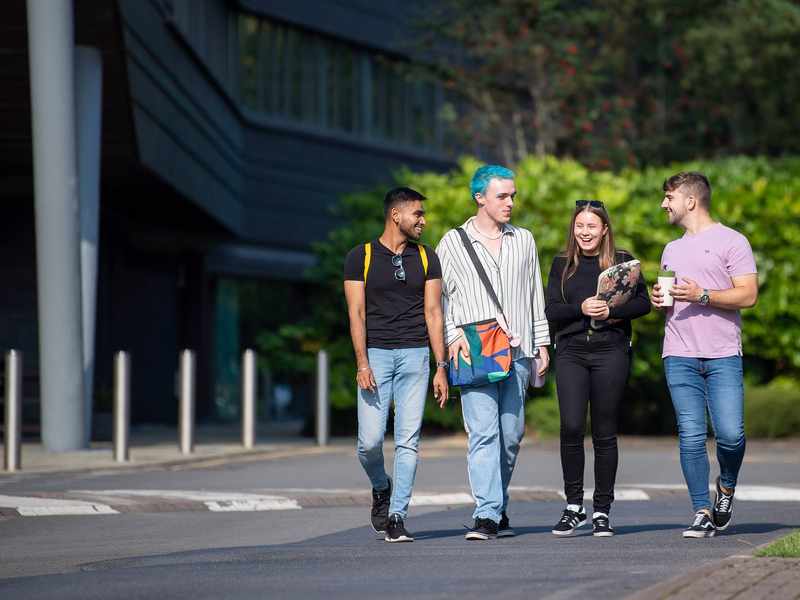 Group of 4 students walking through campus