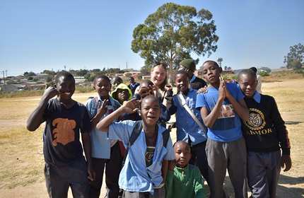 A group of Zambian schoolchildren pose for a photograph with a member of Volunteer Zambia
