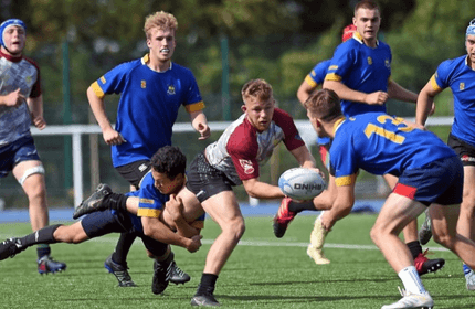 Rugby players compete on a grassy field, showcasing teamwork and athleticism during an intense match.