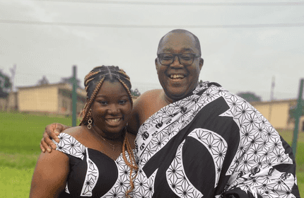 A woman and man in traditional clothing, showcasing a friendly expression and a welcoming demeanor.